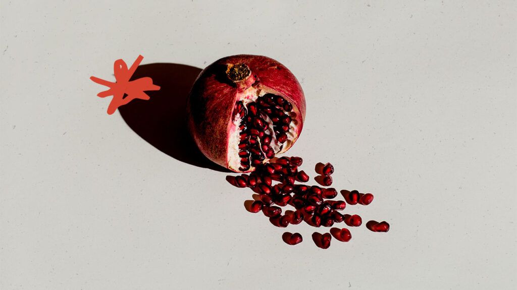 A pomegranate that has burst open on a flat surface