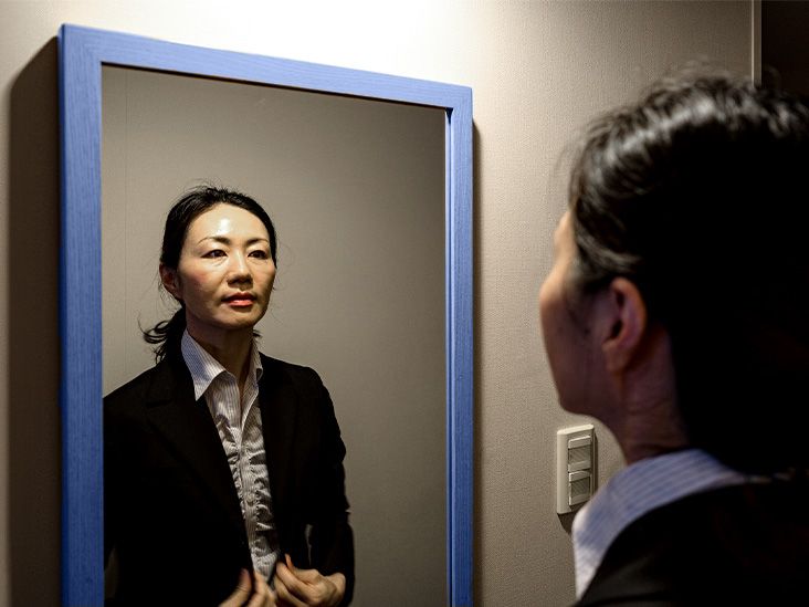 business woman looking at reflection in mirror