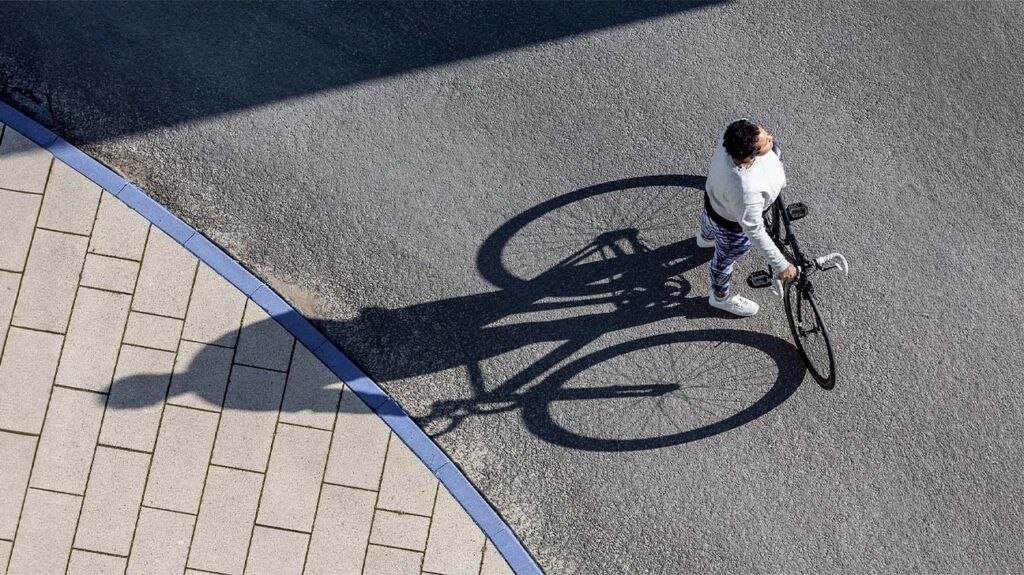 Overhead view of a cyclist and their shadow on concrete