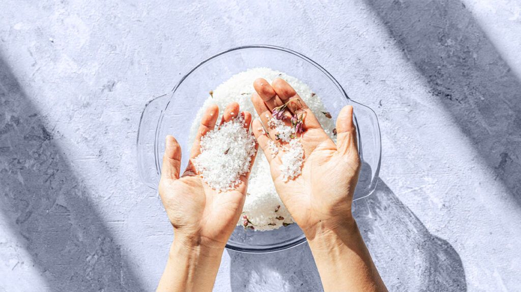 Overhead view of hands sifting salt in a bowl