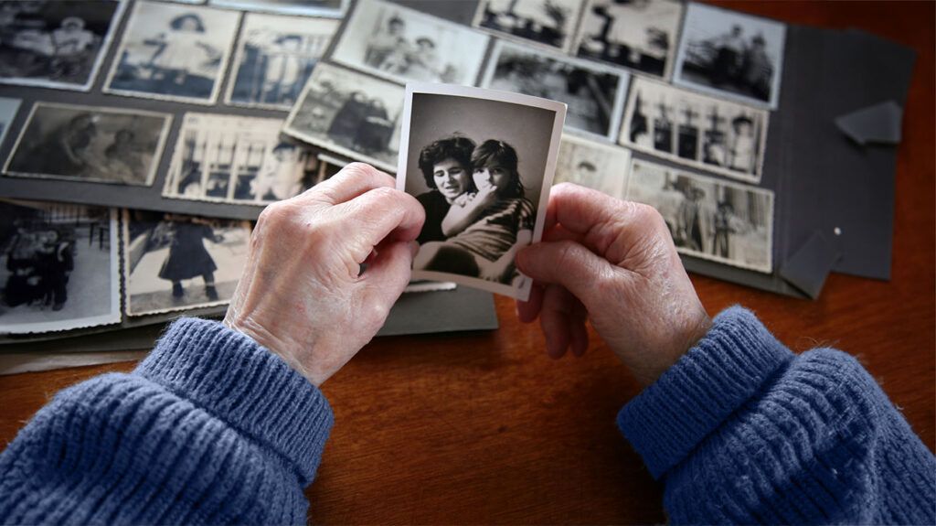 older person's hands holding black and white photo of mother and her daughter
