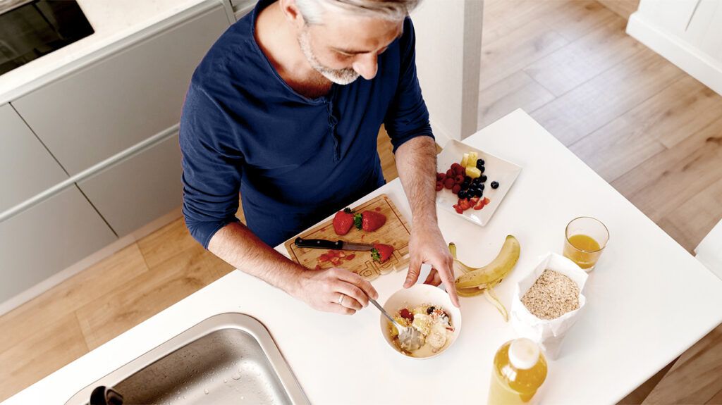 A man with high cholesterol preparing a breakfast with fruits to reduce inflammation.-1