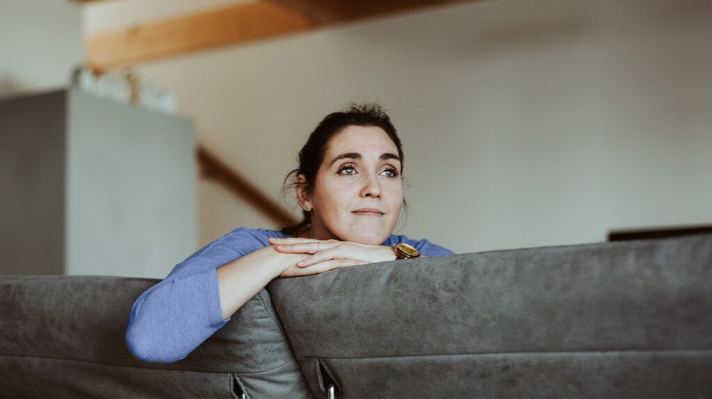 Pensive woman sits on a sofa