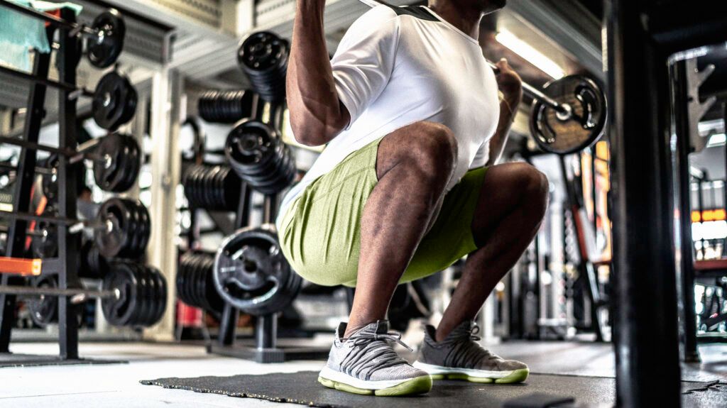 A person is squatting with weights in a gym.