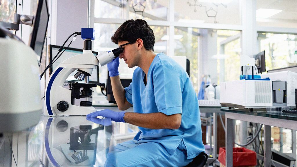 A medical professional is looking through a microscope.