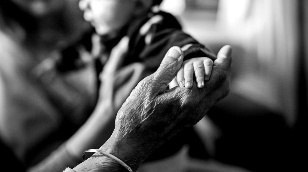 senior and infant touching hands