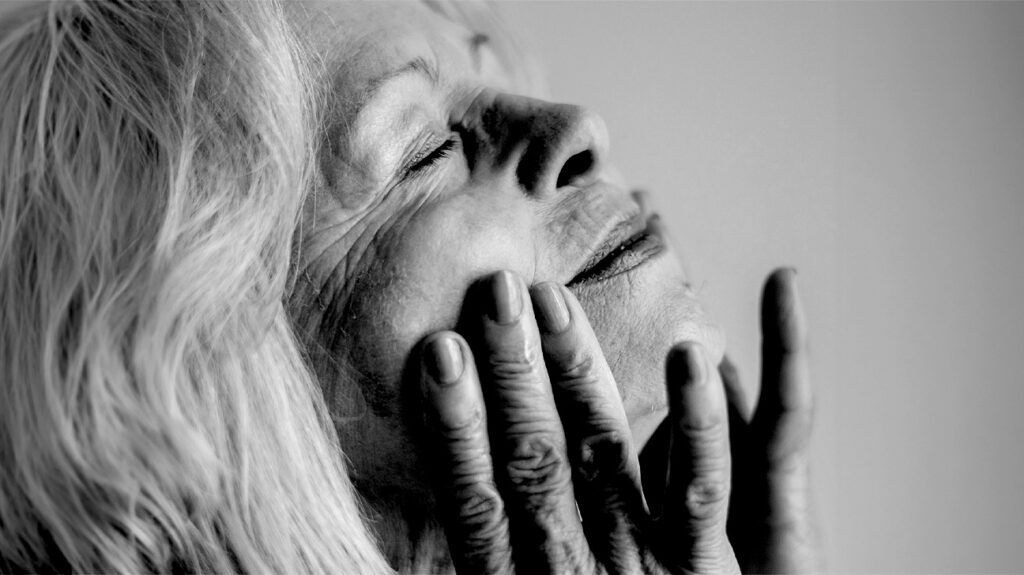 An older woman touching her face.