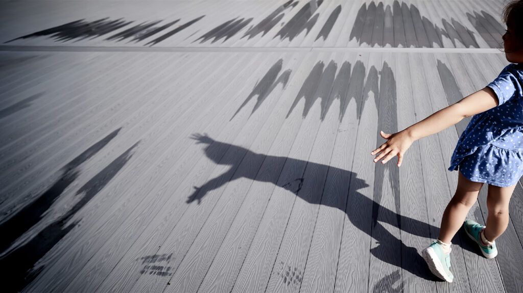 A child with PTSD pointing with a shadow beside them.-1