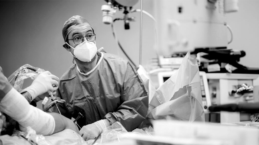A surgeon in an operating room looks at a monitor