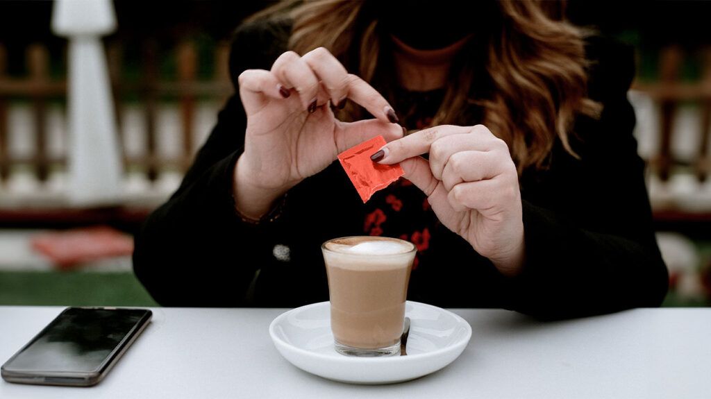 A woman puts artificial sweeteners in her coffee