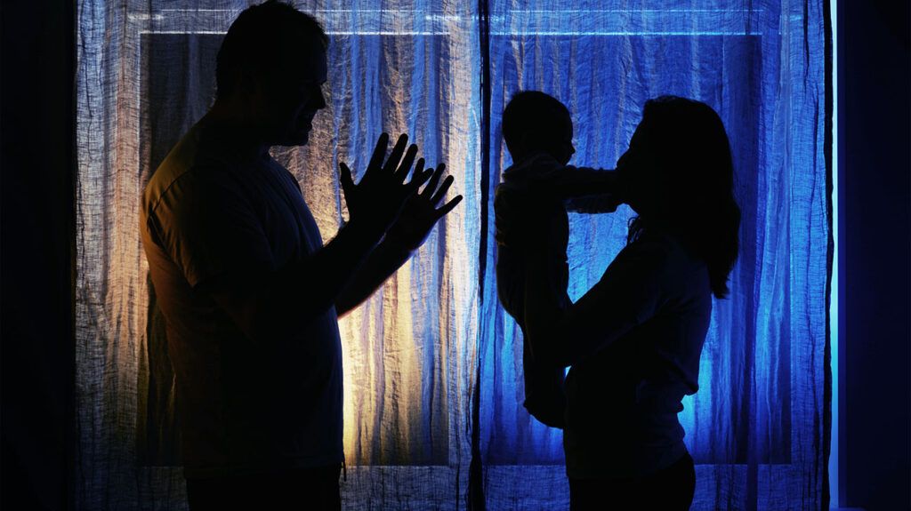 The shadows of two people, one holding an infant, discussing whether ALS is transmissible.-1