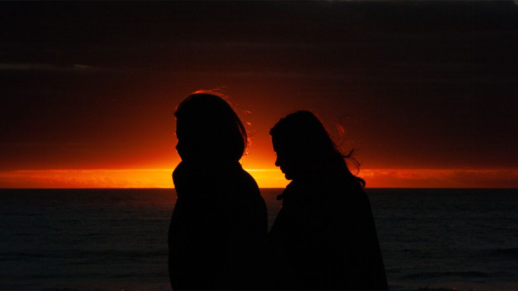 Two women sit as they watch the sunrise