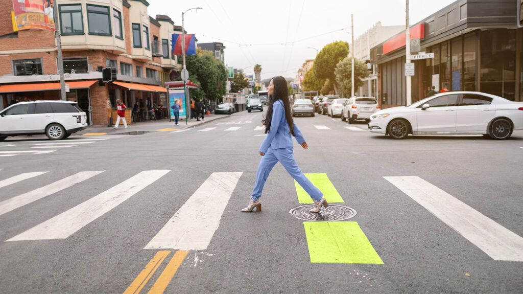 A woman walking over a crosswalk on a city street.