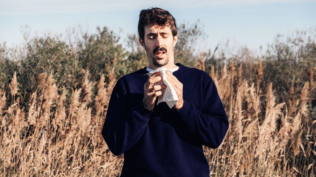 A man in a wheat field coughing up phlegm into a tissue. -1