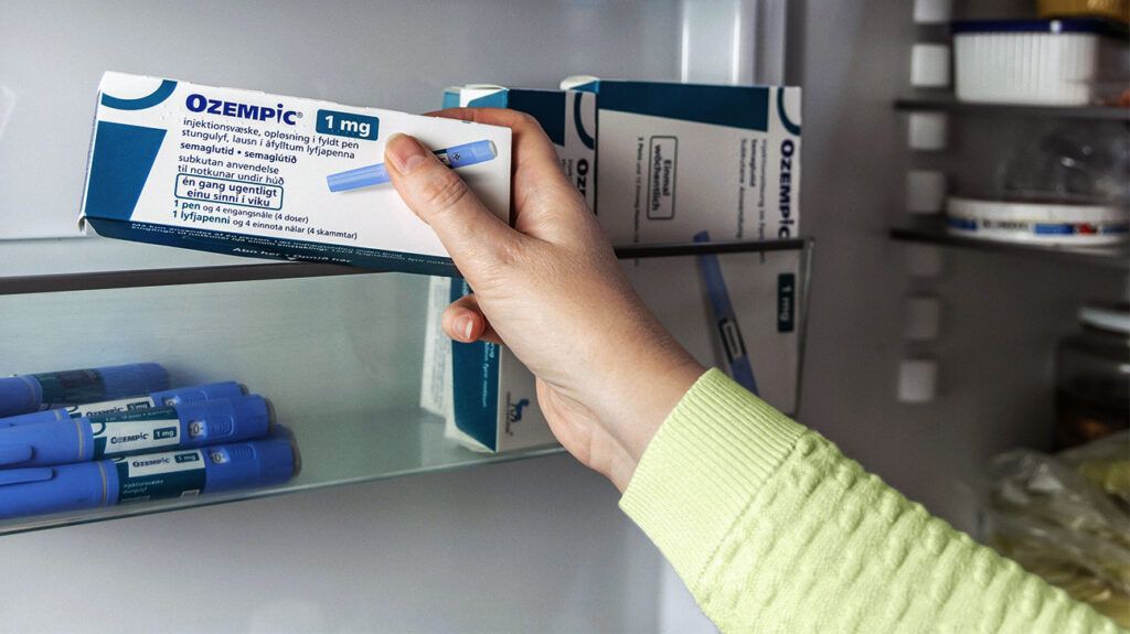 A person holding a box of Ozempic injections for type 2 diabetes management