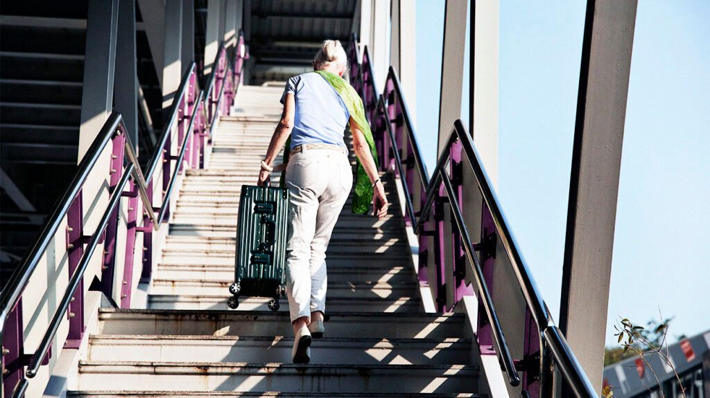 older person carrying luggage on staircase