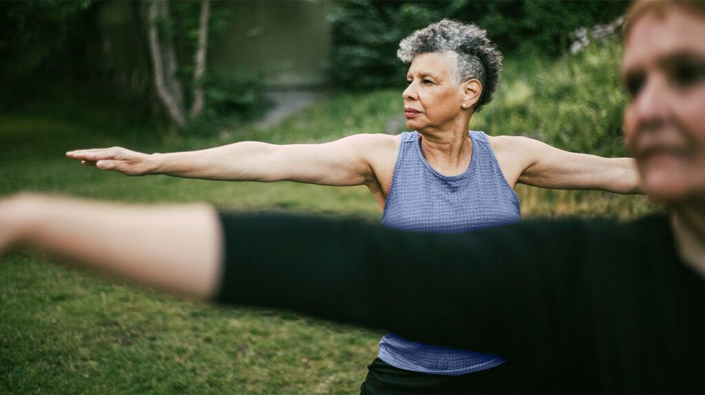 Older females practicing yoga outdoors