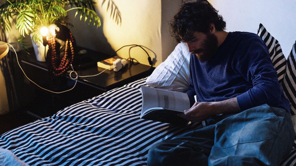 Male lying in bed reading a book