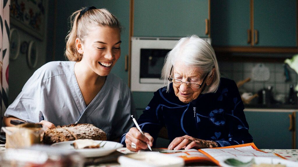 A healthcare professional and a female over 65 sitting at a table together