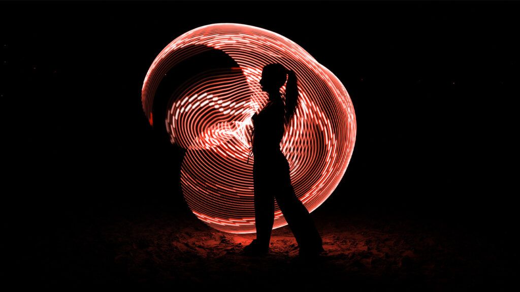 Silhouette of a female in front of swirling colored lights