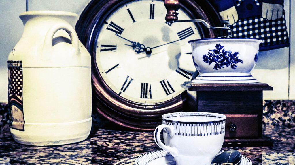 A cup of tea, a tea pot and an analog clock