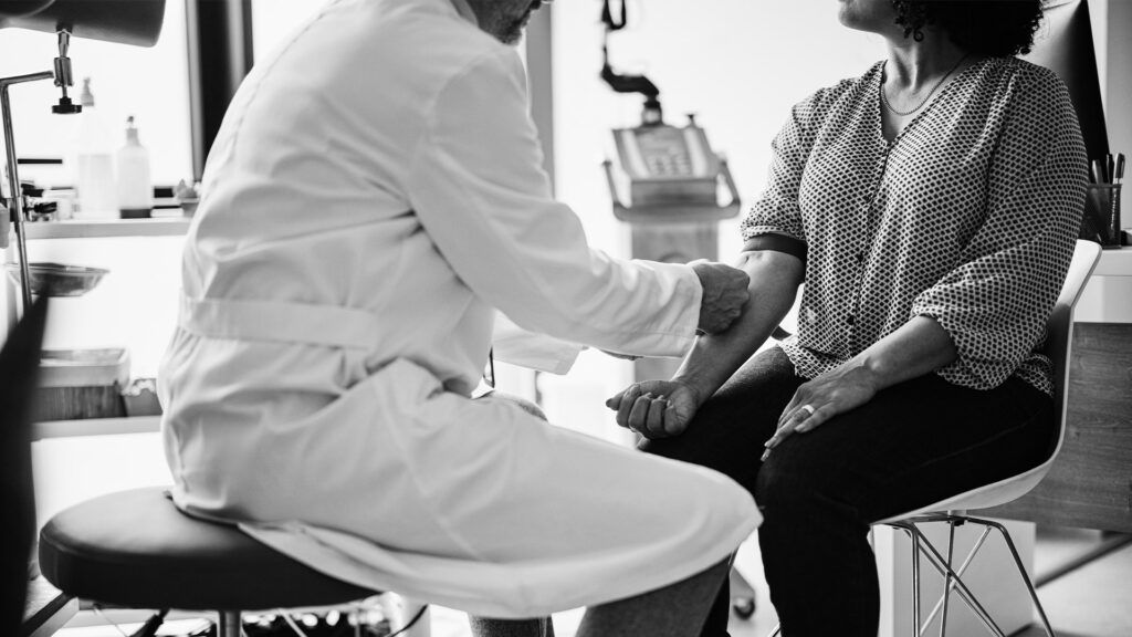 black and white photo of doctor speaking to patient