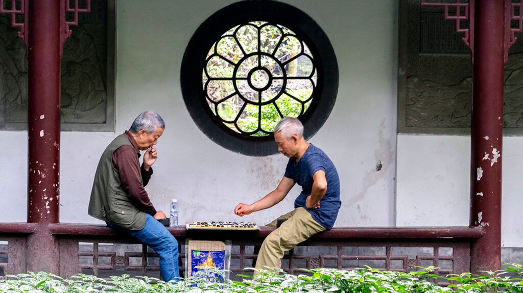 Two older men playing checkers