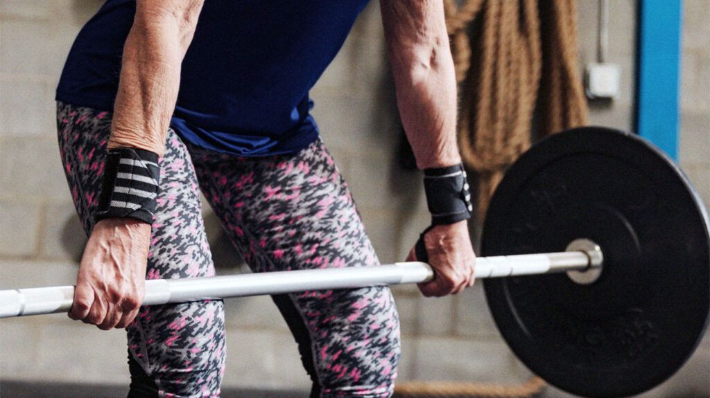 An older adult female deadlifting with a barbell