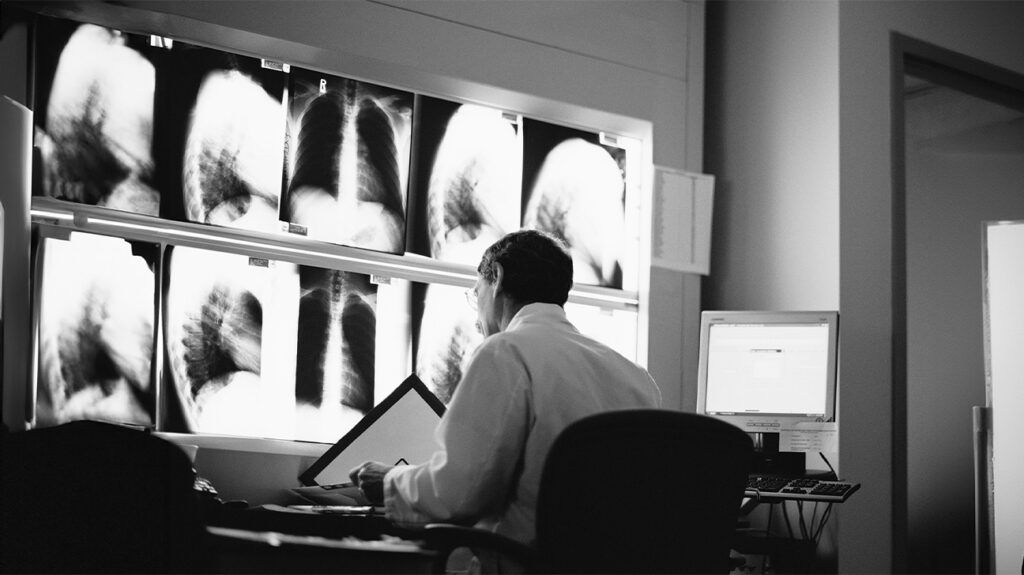 Black and white image of a doctor examining x-rays