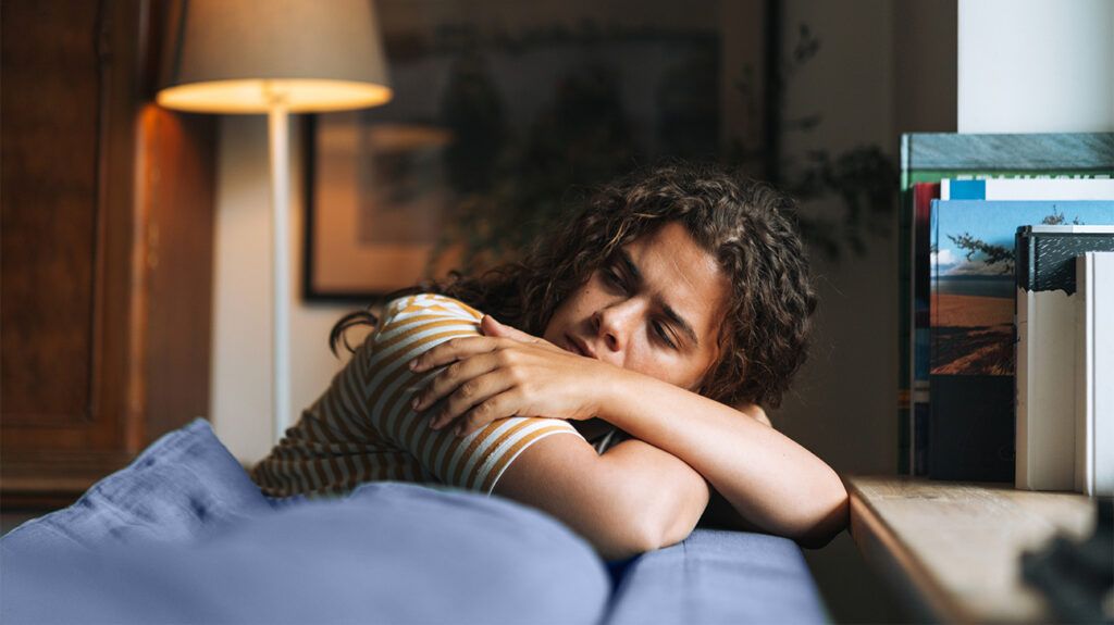 A female looking tired and leaning on the back of a sofa.-1