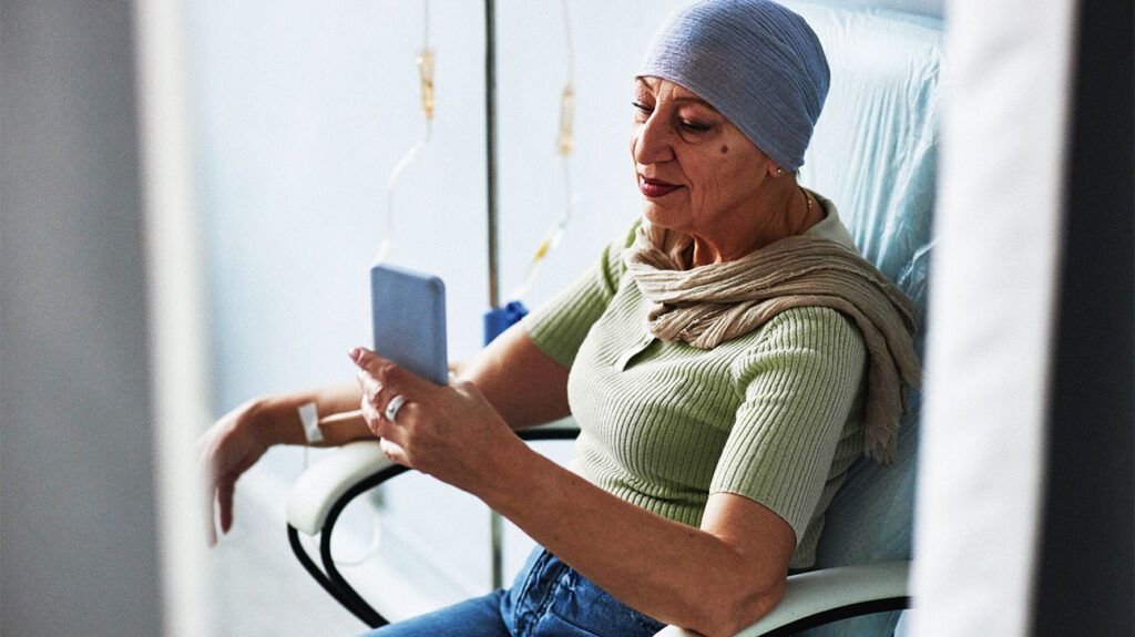 Side view senior woman with IV drip and using smartphone