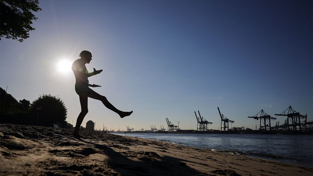 A man prepares to jump into the sea on the beach