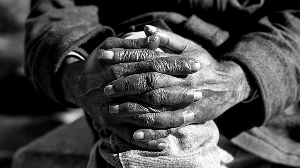 black and white photo of older person's hands clasping their knee