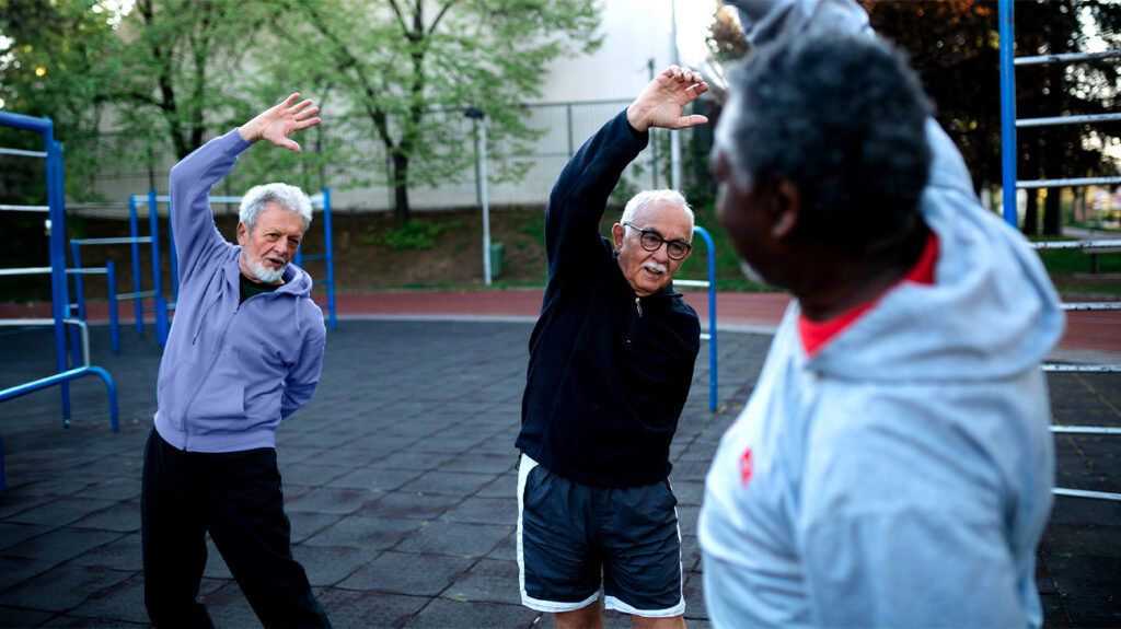 Older males in an outdoor SilverSneakers exercise class