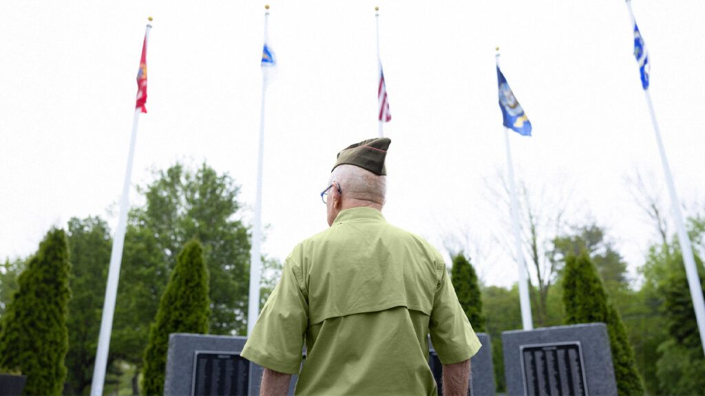 A military veteran over 65 standing in front of a war memorial