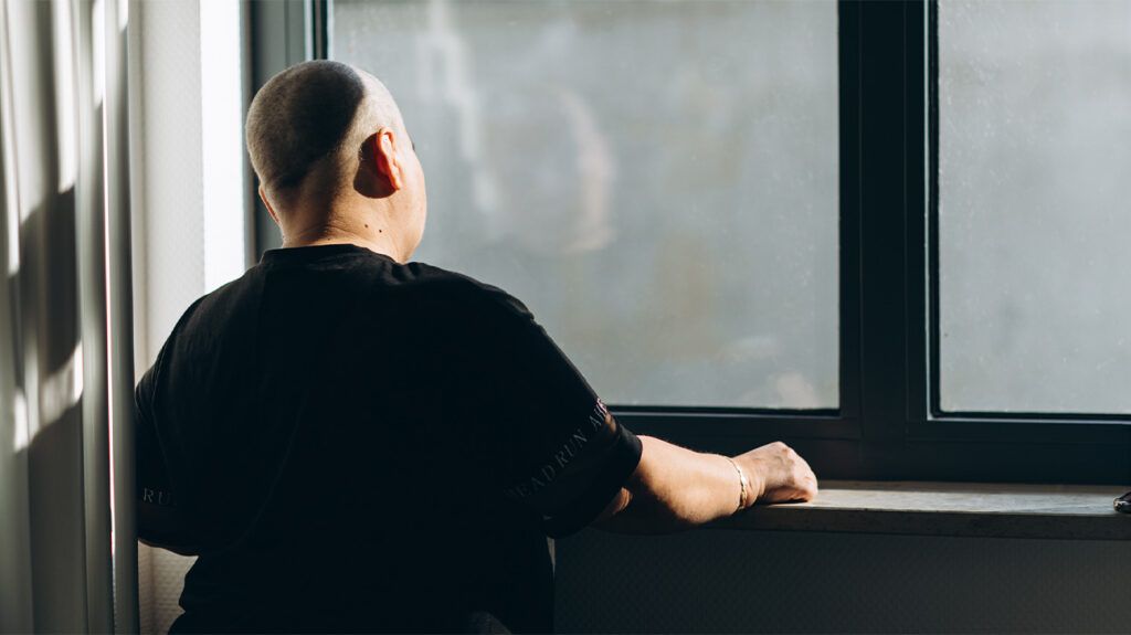 Female chemotherapy patient standing at a window