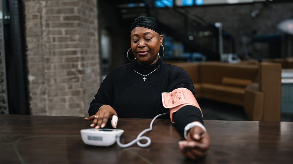 Black woman using blood pressure monitor