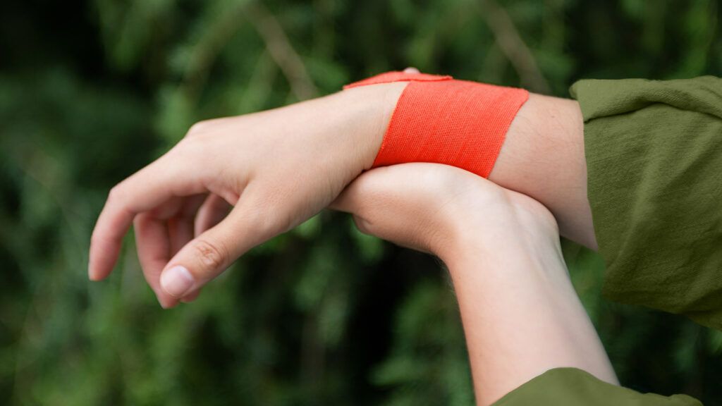 Closeup of red kinesio tape on a person&rsquo;s wrist.