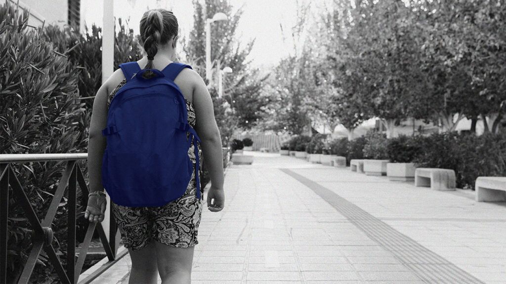 Black and white image of a girl walking down a street