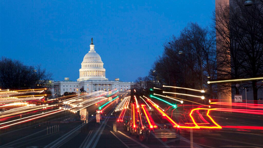 the United States Capitol building at night, traffic lights creating lines with a long exposure shot