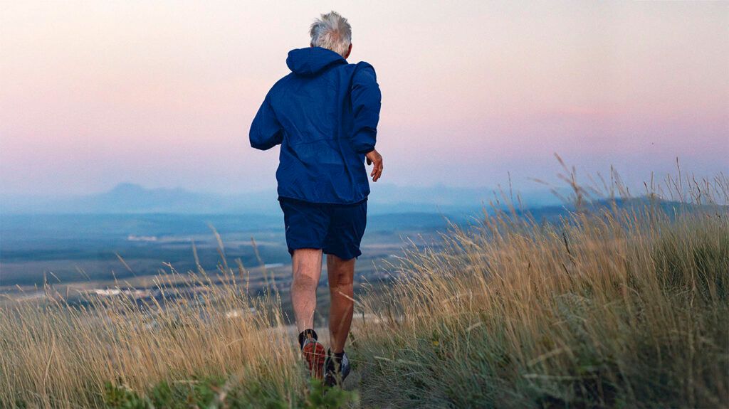 Senior man runs through grasses at sunset-1