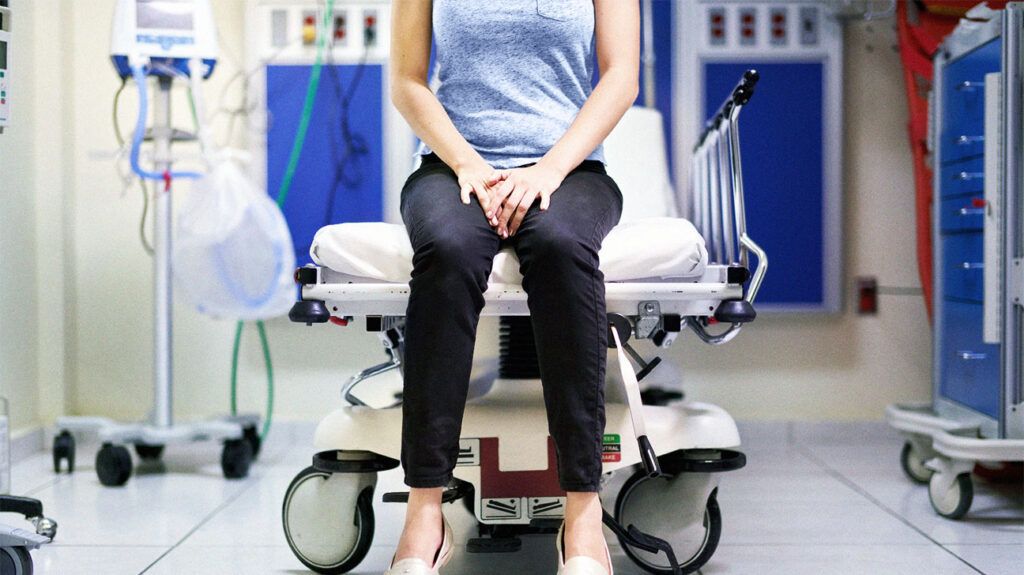 A woman sitting on an examination chair waiting to be seen by a doctor