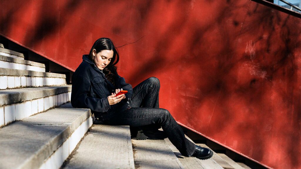 Woman sitting on stairs and texting on her smartphone. -2
