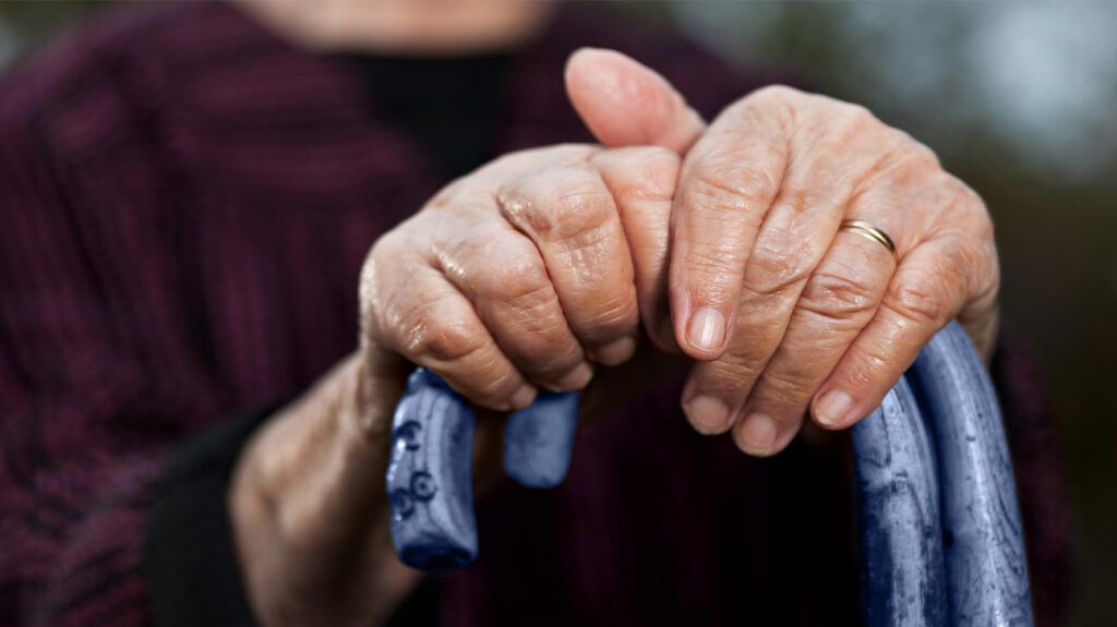 An older adult grabbing a cane to help himself get up