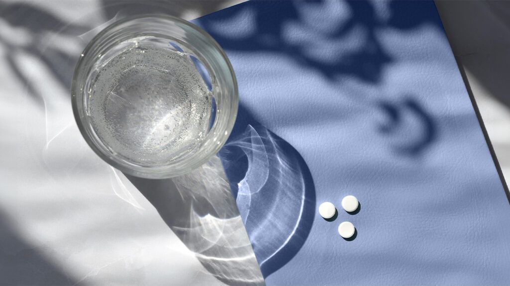 Pills and a glass of water on a table
