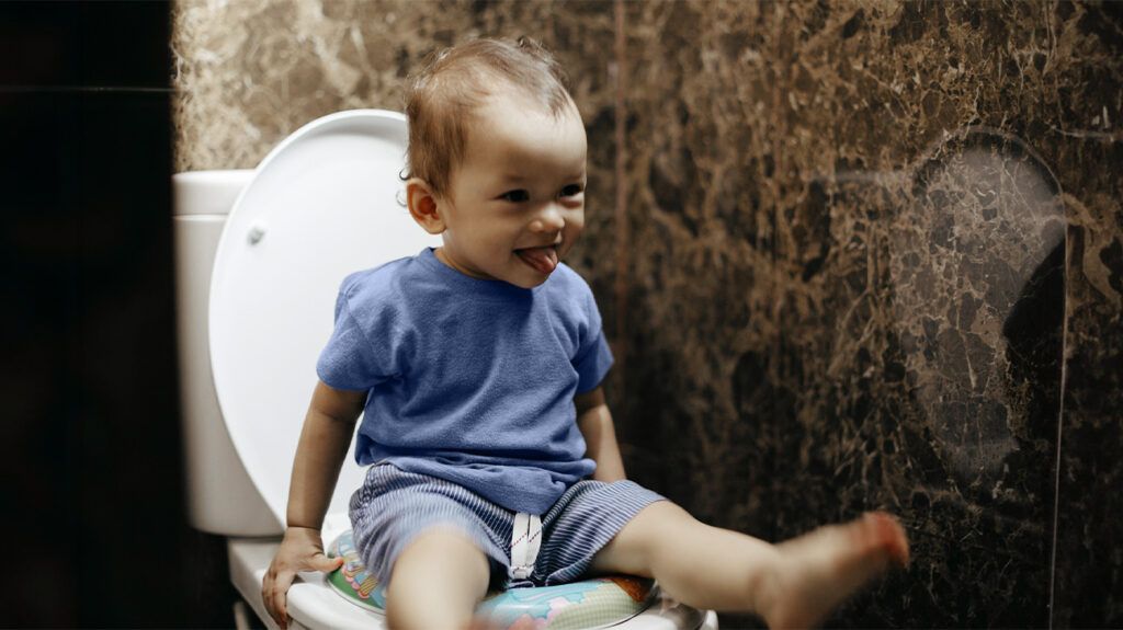 Toddler smiling on a toilet