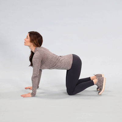 A woman performing a Cat Cow yoga pose. 