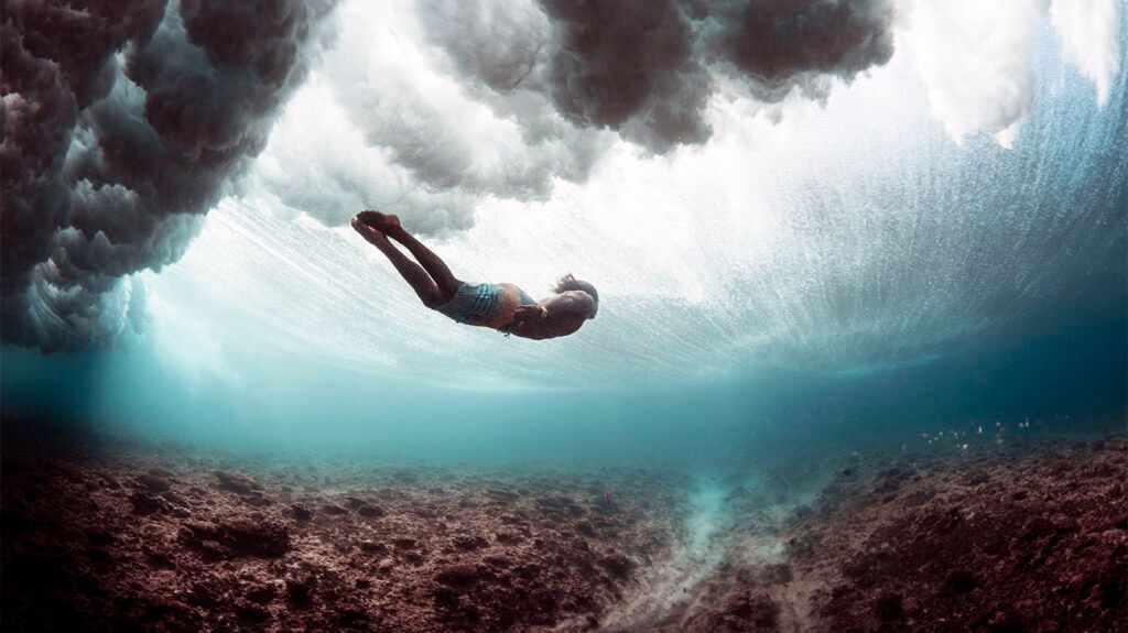 silhouette of young person free diving in the sea