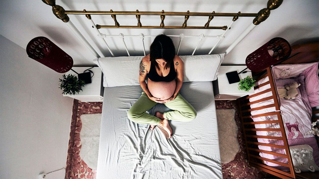 Pregnant person sitting on bed