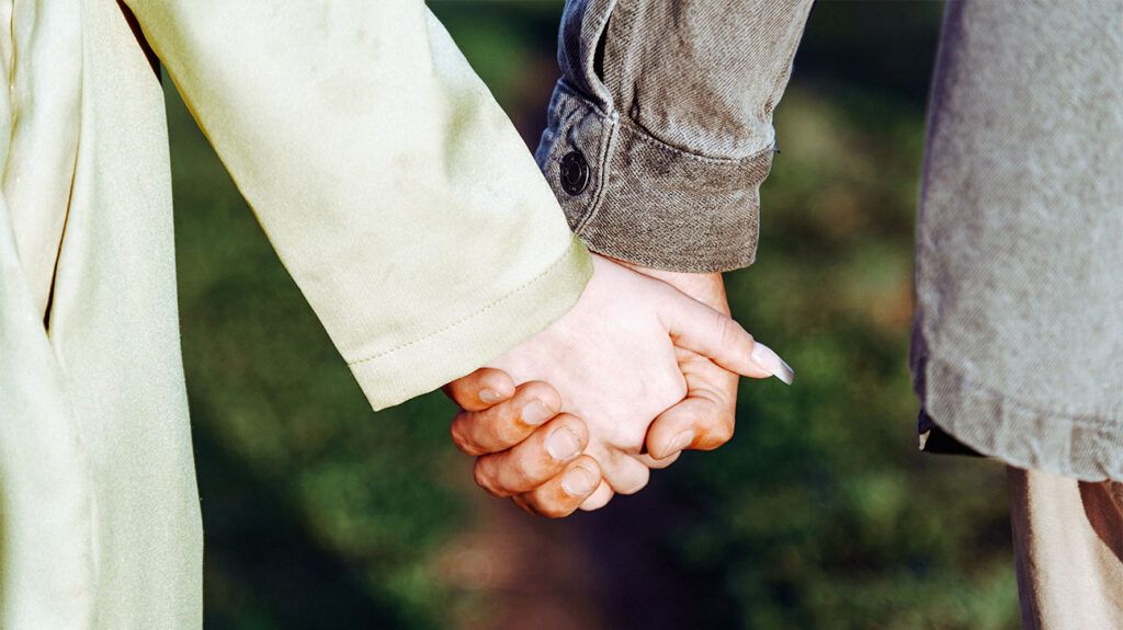 A close-up shot of two people holding hands.-2